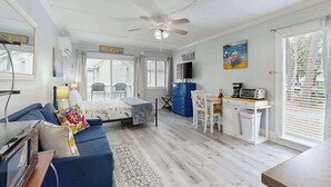 A room with a bed, a desk, a chair, a ceiling fan, and a window with blinds. - Charming & sun-filled studio with great patio & W/D - close to beach (Edisto Beach)