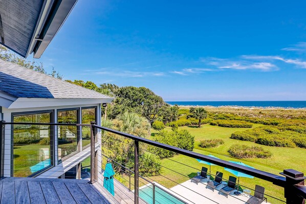 A balcony with a view of the ocean, a pool, and a well-maintained lawn. - Stunning Oceanfront Hideaway with Private Pool, Deck, and Yard - Dogs Welcome (Hilton Head)
