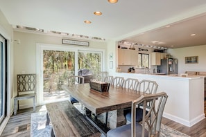 A spacious dining area with a wooden table and chairs, a kitchen with white cabinets, and a sign reading 'THIS IS OUR HAPPY PLACE.' - Stunning Oceanfront Hideaway with Private Pool, Deck, and Yard - Dogs Welcome (Hilton Head)