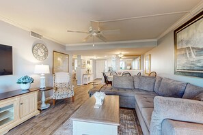 A living room with a sectional sofa, a coffee table, a lamp, a clock, and a ceiling fan. - Amazing oceanfront 2BR 2BA 1st floor condo with pool, hot tub, tennis, fitness area, & W/D (Hilton Head)