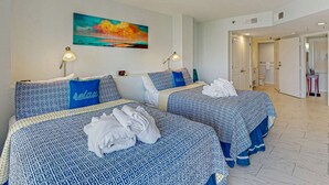 Une chambre d’hôtel avec deux lits, un tableau accroch é au mur et une salle de bain visible à travers une porte ouverte.