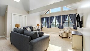 Ein geräumiges Schlafzimmer im Loft-Stil mit großem Fenster, einer Couch, einem Sessel und einem Schreibtisch.