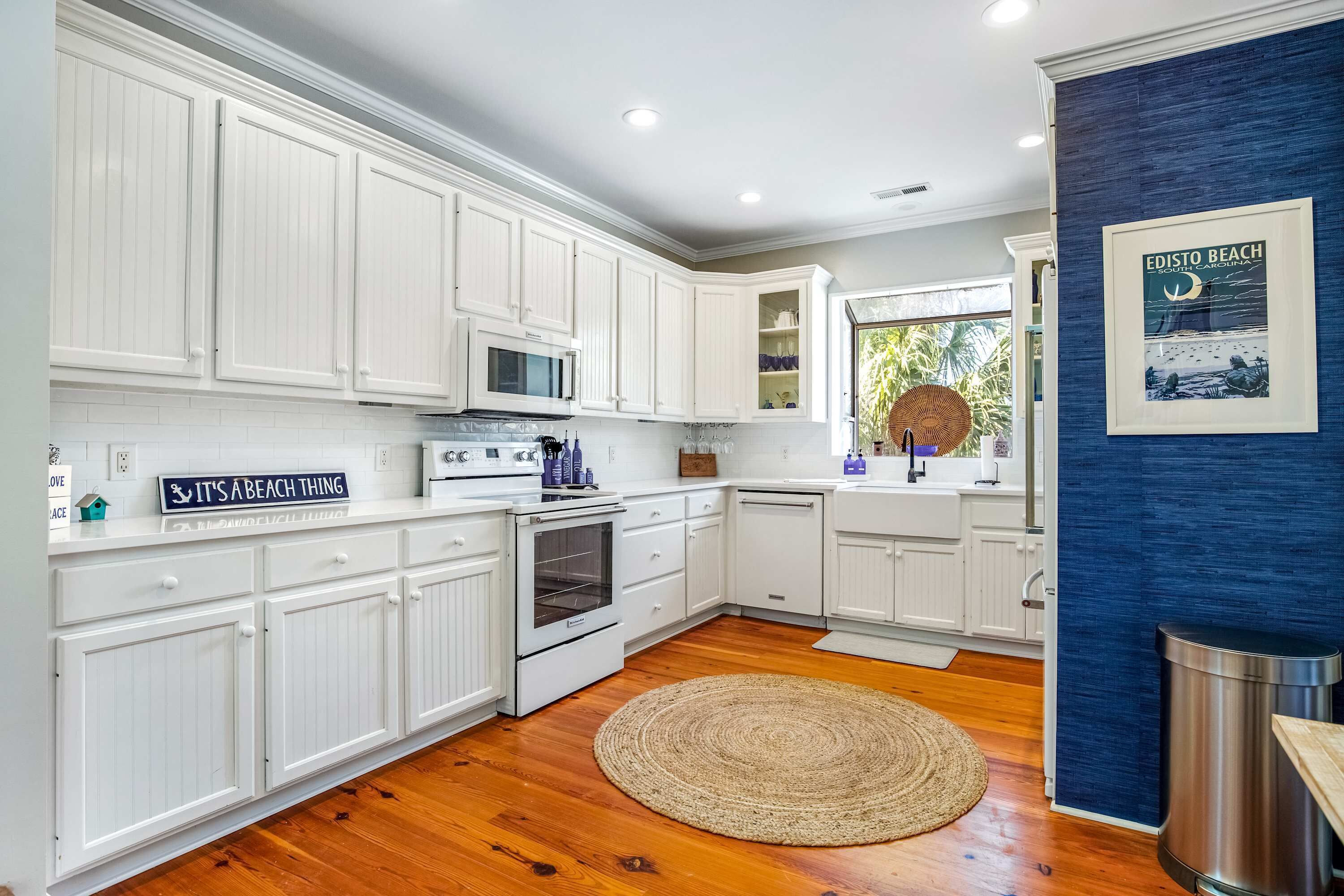 A kitchen with white cabinetry, a microwave, an oven, and a wooden floor.