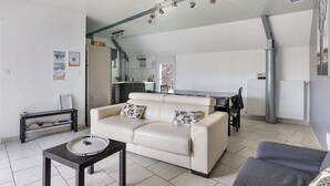 Un salon moderne avec un canapé, une petite table et un coin repas comprenant une table et des chaises.