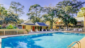 A swimming pool with lounge chairs, a small building with a porch, and surrounding trees. - Sunny Villa with Spacious Decks, Al Fresco Dining, & Shared Pool - Nearby Beach Access (Hilton Head)