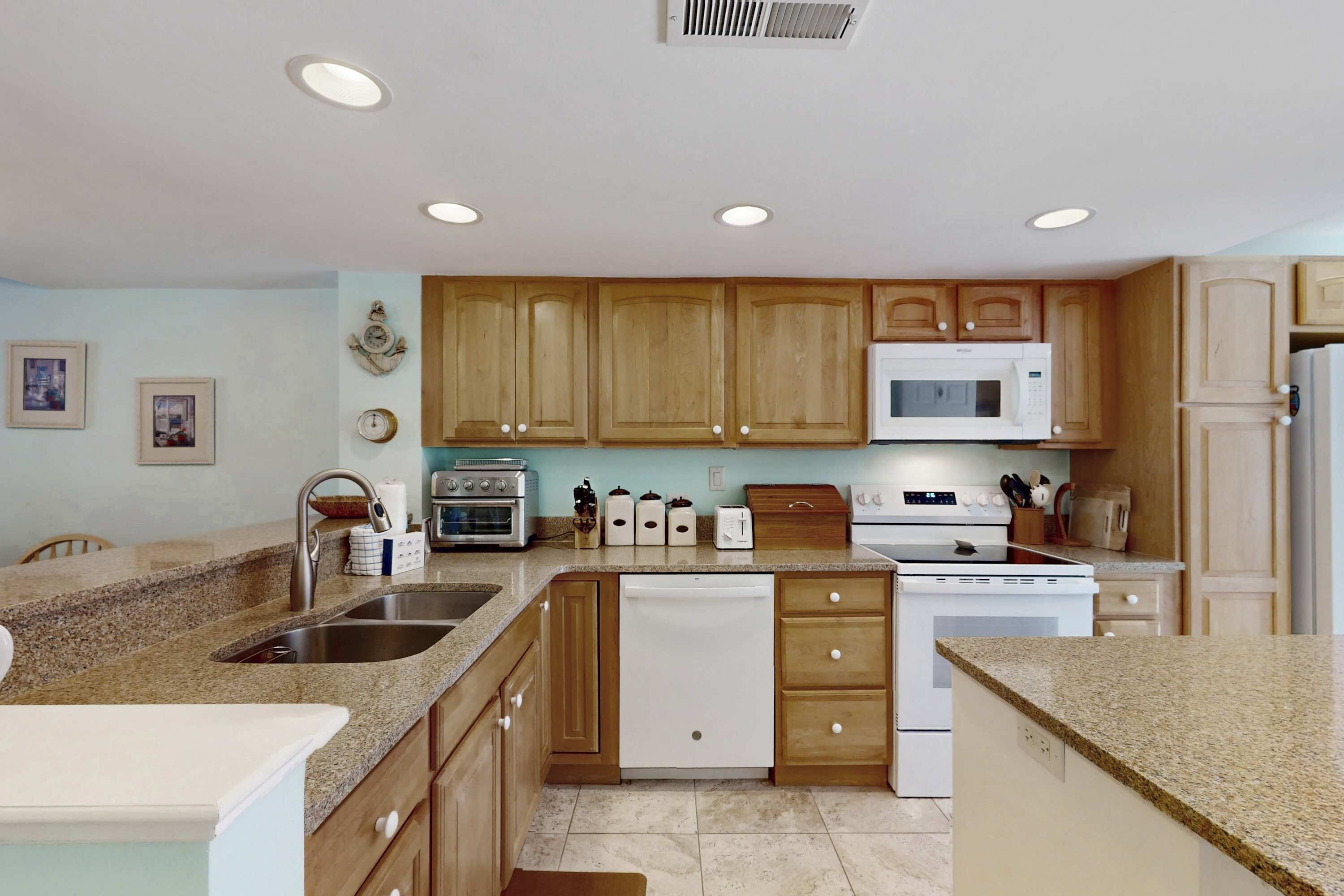A kitchen with wooden cabinets, a microwave, an oven, a dishwasher, and a granite countertop.