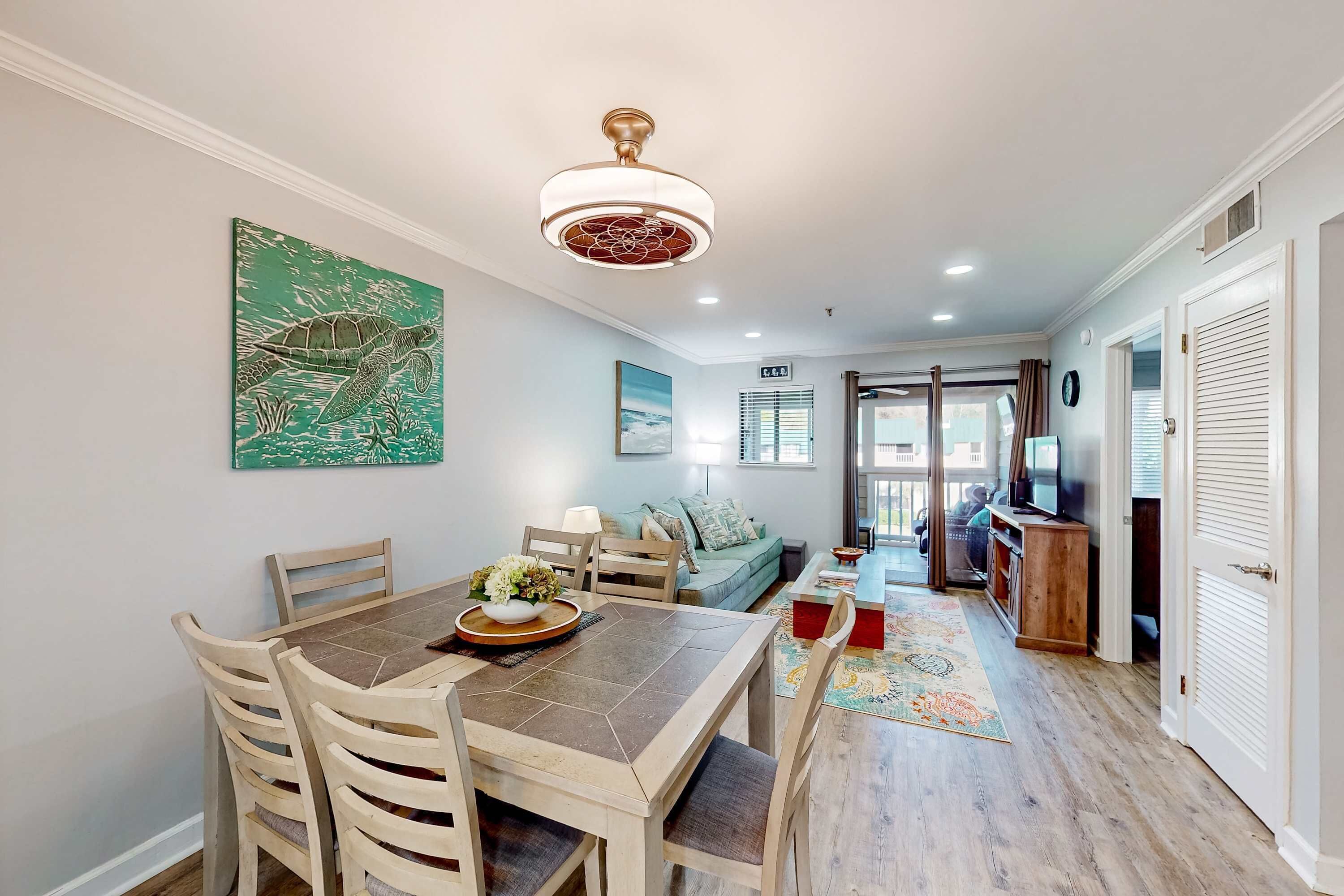 A dining area with a table and chairs, a ceiling fan, and a wall-mounted painting.