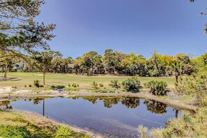 Ein Golfplatz mit Teich, Bäumen und blauem Himmel.