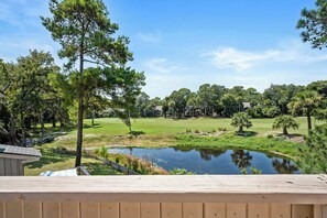 Ein Wohnhaus mit Teich, einem Golfplatz im Hintergrund und einer hölzernen Terrasse im Vordergrund.