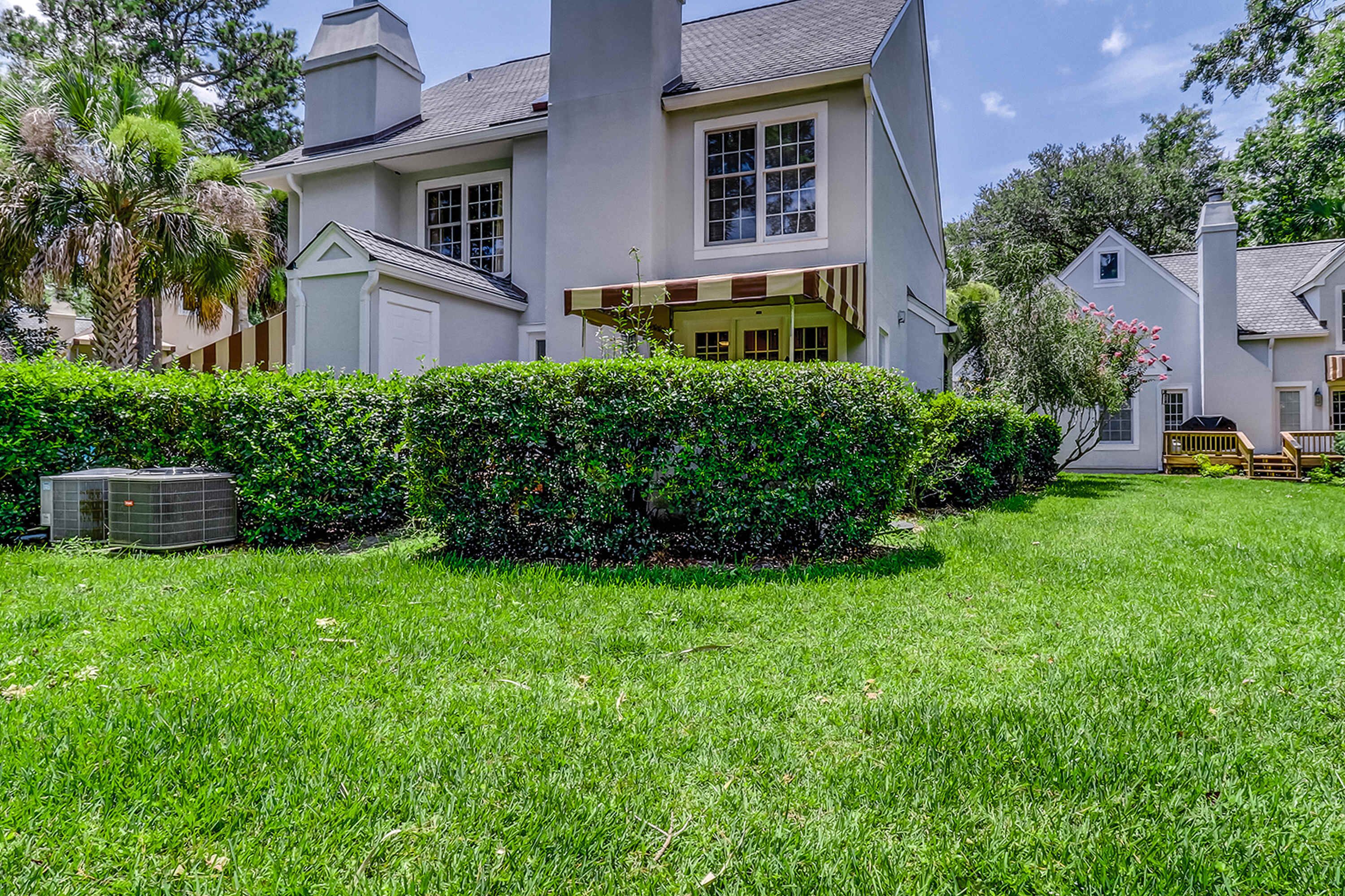 A two-story house with a covered porch, a well-maintained lawn, and a large air conditioning unit.