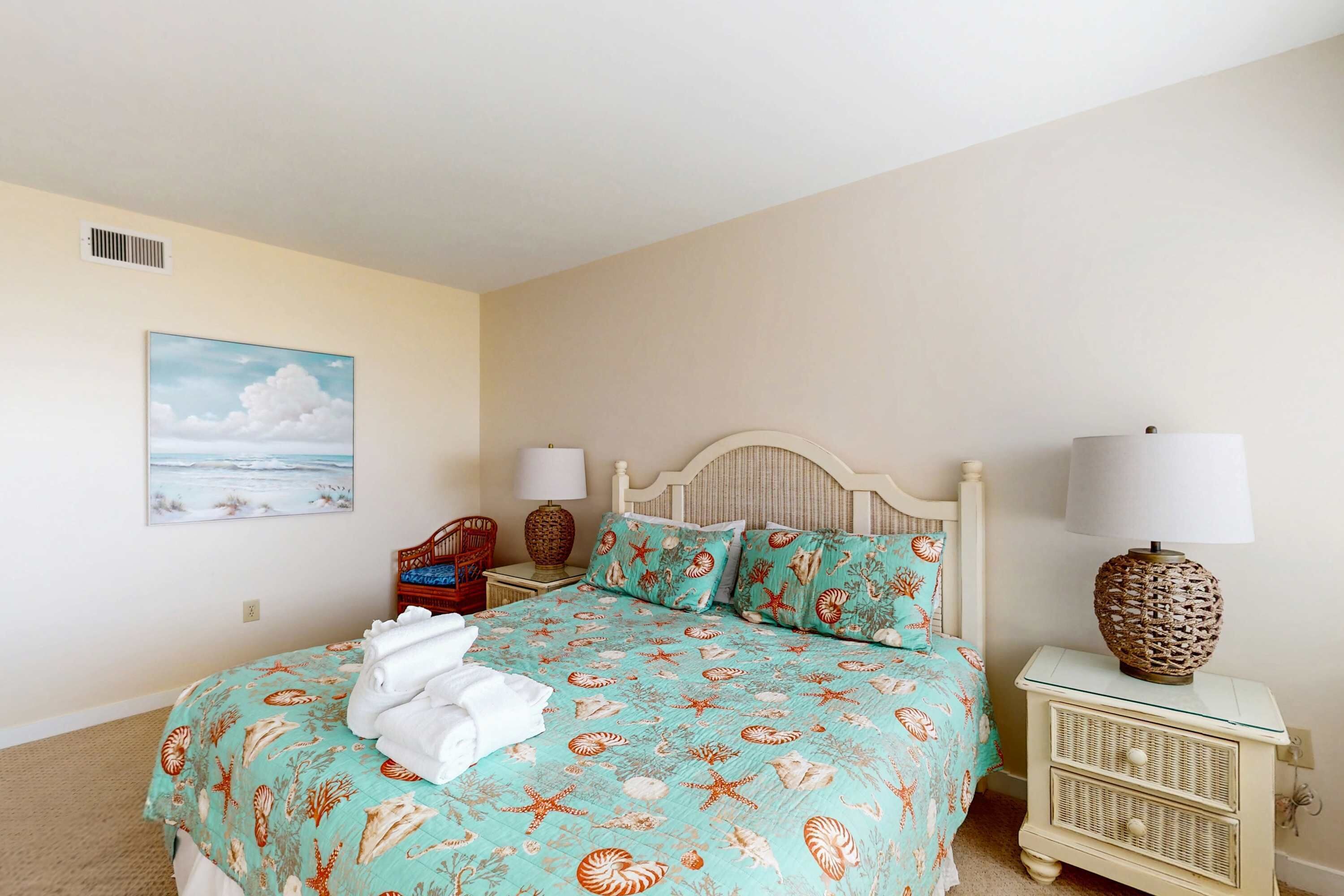 Une chambre à coucher avec un lit, deux tables de chevet, une lampe, une chaise et un tableau accroché au mur.