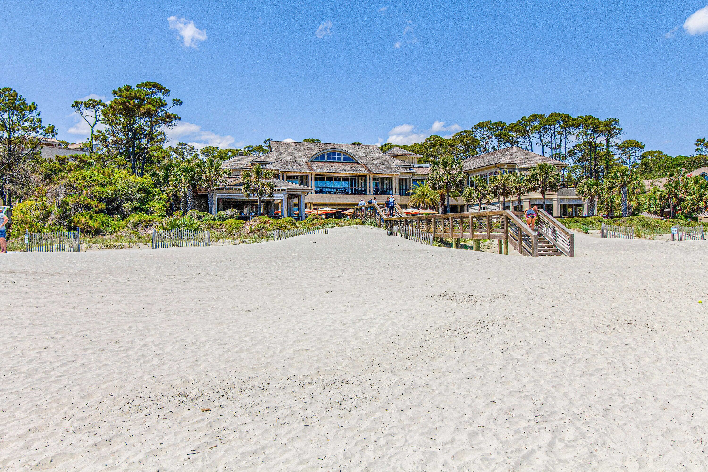 Una propiedad frente a la playa con un edificio grande, una playa de arena y una escalera de madera que lleva a la entrada.