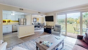 A spacious living area with a kitchen, dining area, and a balcony with a view. - Bay view villa with balcony, AC, & W D  walk to beach (Hilton Head)
