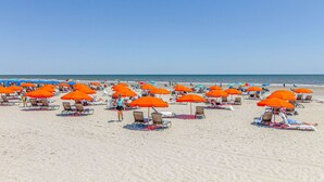 A beach with rows of orange umbrellas and beach chairs. - Bay view villa with balcony, AC, & W D  walk to beach (Hilton Head)
