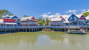 A waterfront hotel with multiple buildings, a dock, and a boat. - Bay view villa with balcony, AC, & W D  walk to beach (Hilton Head)