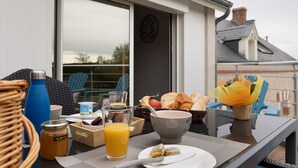 Une table de petit-déjeuner avec un bol, un verre de jus d’orange, une bouteille et une assiette contenant des aliments.