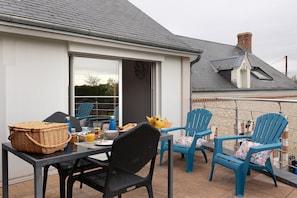 Eine Terrasse mit Tisch, Stühlen und einem Korb.