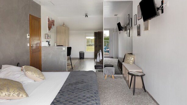 Une chambre d’hôtel moderne équipée d’un lit, d’un bureau, d’un téléviseur fixé au mur et offrant une vue sur l’extérieur.