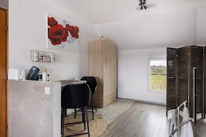 Ein Zimmer mit einem Holzschrank, einem Essbereich mit Stühlen, einer Küchenzeile mit Geräten und einem Fenster mit Blick.