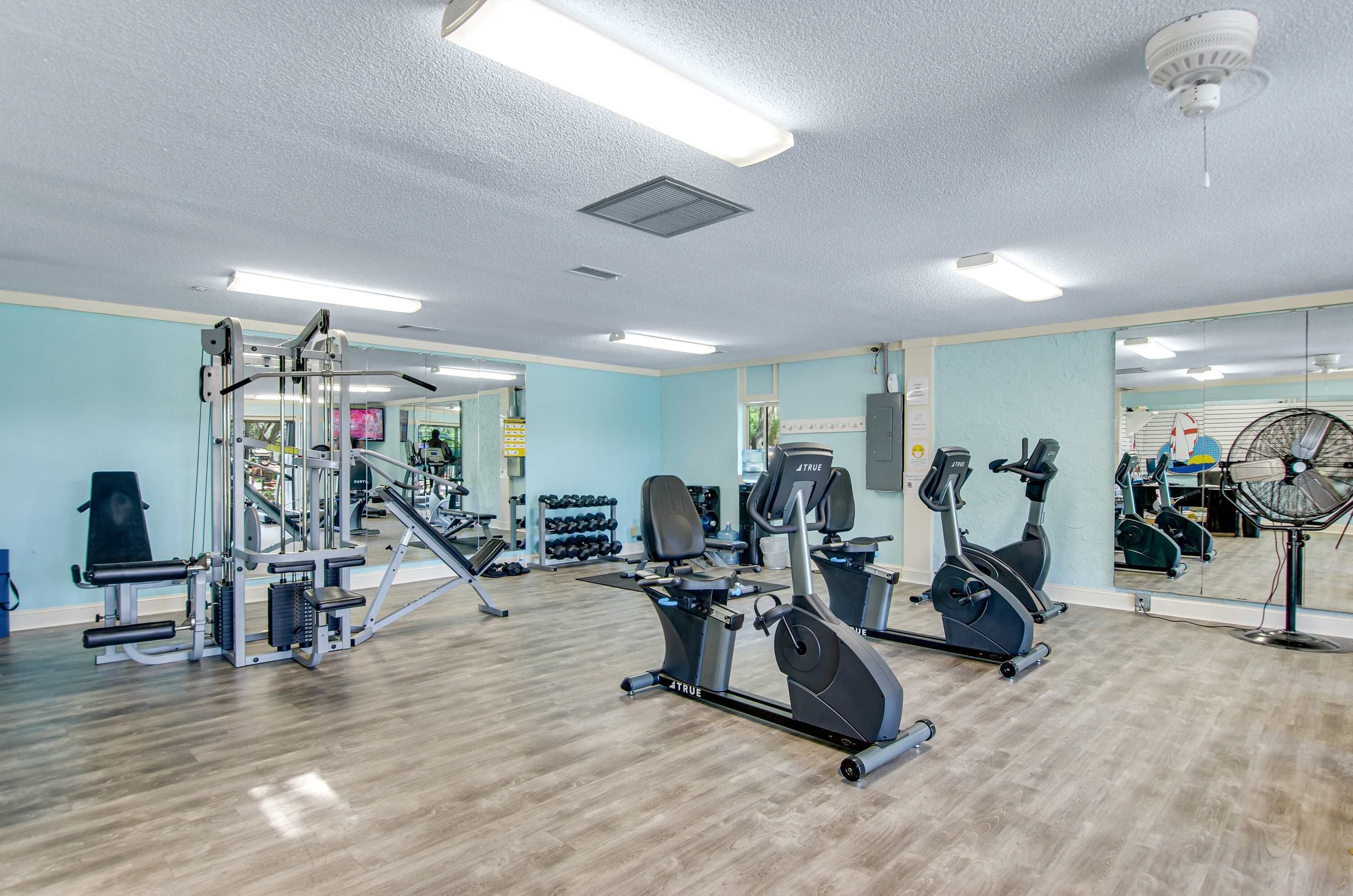 A gym with exercise equipment, a mirror, and a fan.