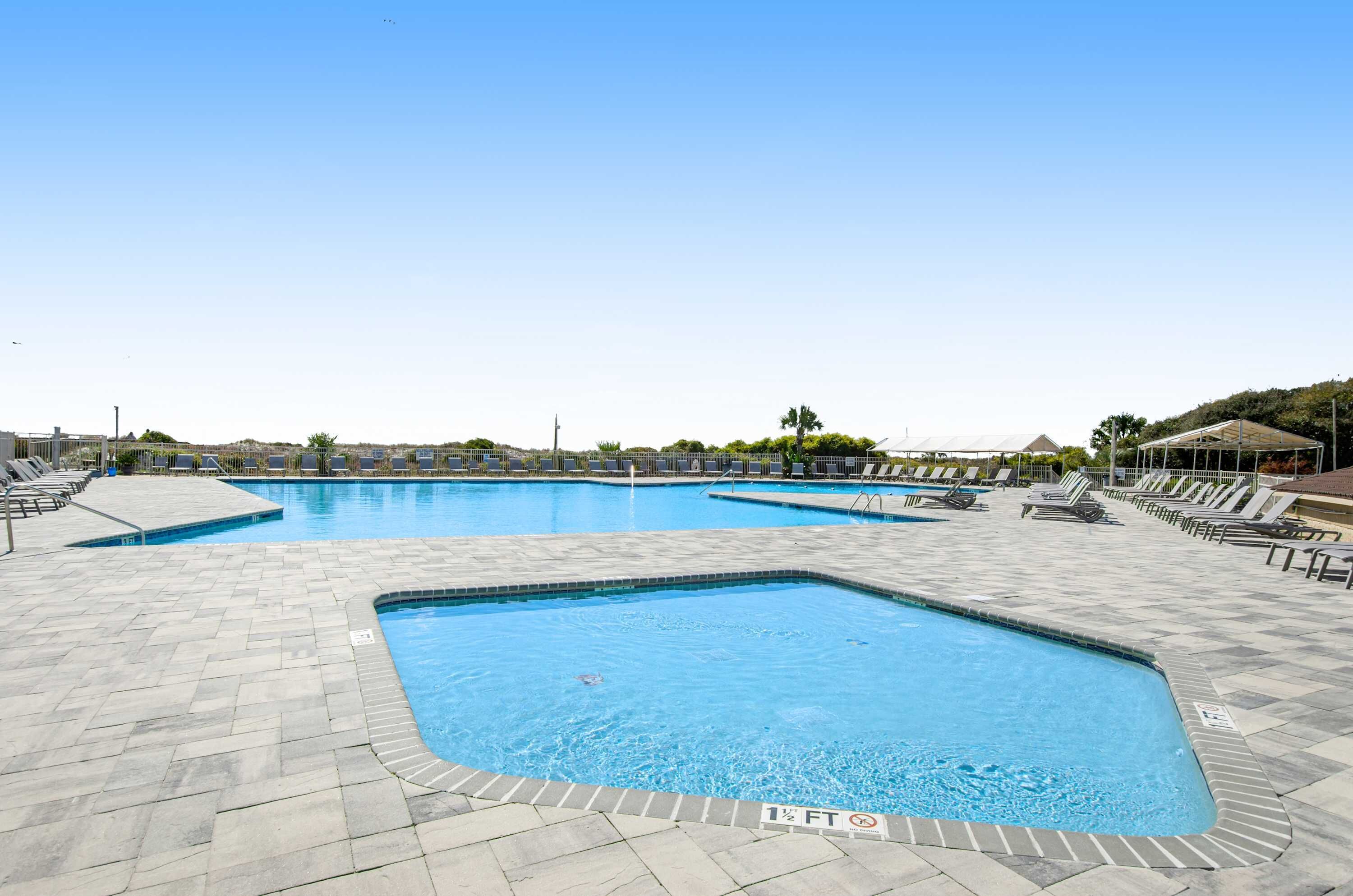 A swimming pool with multiple lanes, lounge chairs, and a tiled deck.