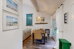A dining area with a wooden table and wicker chairs, a hanging light fixture, and a green bench. - Cheerful condo with shared pool, close to beach, golf, tennis and shopping (Hilton Head)