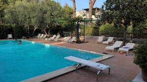 Une piscine avec des chaises longues et une pergola.