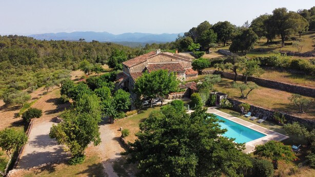 Uma villa com piscina, rodeada por árvores e um cenário montanhoso.