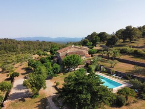 Eine Villa mit Swimmingpool, umgeben von Bäumen und einem Bergpanorama.