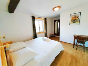 Ein Hotelzimmer mit Bett, Schreibtisch, Stuhl, Spiegel und einem Bild an der Wand.
