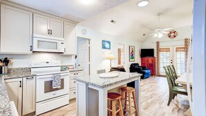 A kitchen with a microwave, oven, and bar stools. - Spacious Tropical Home w/ Patio, Free WiFi & Screened-In Porch (Edisto Beach)