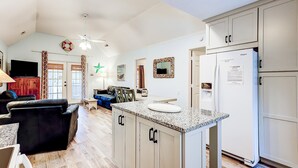 A spacious living area with a kitchen island, a dining table, and a flat-screen TV. - Spacious Tropical Home w/ Patio, Free WiFi & Screened-In Porch (Edisto Beach)