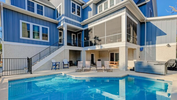 A multi-story building with a swimming pool, outdoor seating, and a covered patio area.