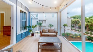 A balcony with a wicker table, a beige sofa, and string lights.