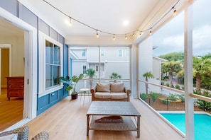 A balcony with a wicker table, a beige sofa, and string lights. - North Forest Beach home with a private pool and four primary suites (Hilton Head)