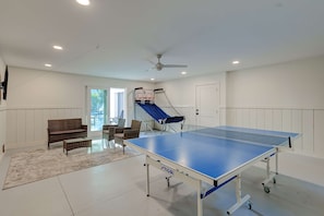 A ping pong table in a room with a ceiling fan, a bench, and a small seating area. - North Forest Beach home with a private pool and four primary suites (Hilton Head)