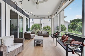 A covered outdoor seating area with wicker furniture, a ceiling fan, and string lights. - North Forest Beach home with a private pool and four primary suites (Hilton Head)