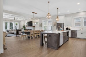 A modern kitchen with a central island, wooden flooring, and pendant lighting. - North Forest Beach home with a private pool and four primary suites (Hilton Head)