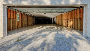 A covered garage with a concrete floor and wooden walls.