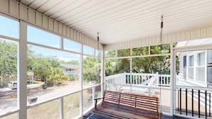 A covered porch with a wooden bench, large windows, and a white railing. - A Block and a Half to the Beach Dog-Friendly Home w/ Screened Porch & WiFi (Edisto Beach)