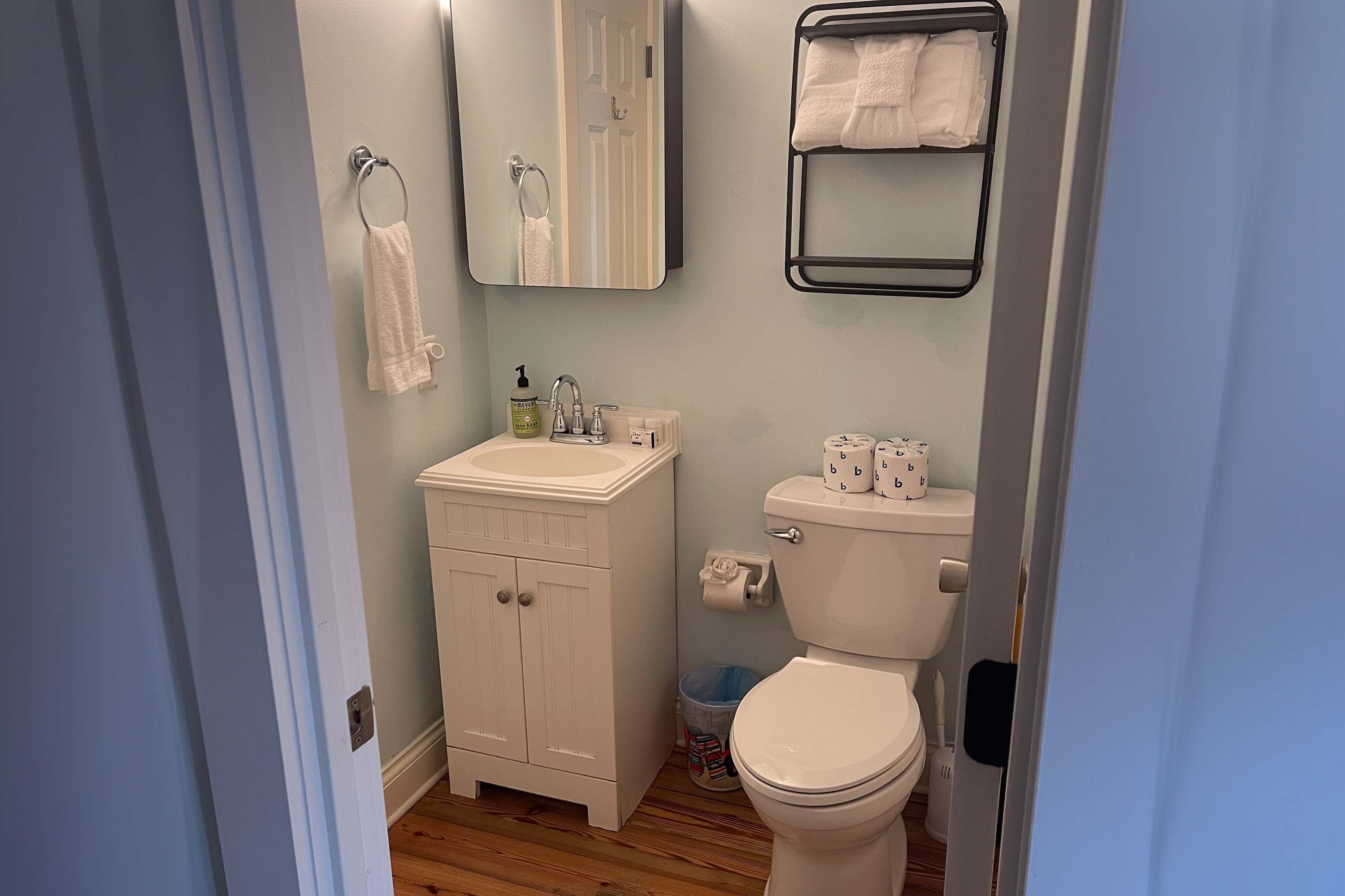 A bathroom with a toilet, sink, mirror, and towel rack.