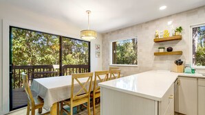 A kitchen with a dining area, large windows, and a view of trees. - Walk to Beach 2BR with loft Condo on Beautiful Edisto Beach, SC (Edisto Beach)