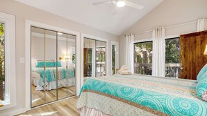 A bedroom with a large bed, a ceiling fan, and a sliding glass door leading to an outdoor area. - Walk to Beach 2BR with loft Condo on Beautiful Edisto Beach, SC (Edisto Beach)