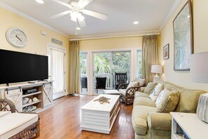 A living room with a television, a white coffee table, a sofa, and a ceiling fan. - Top-floor 3rd-row condo with balcony, AC, outdoor pool & beach access (Edisto Beach)