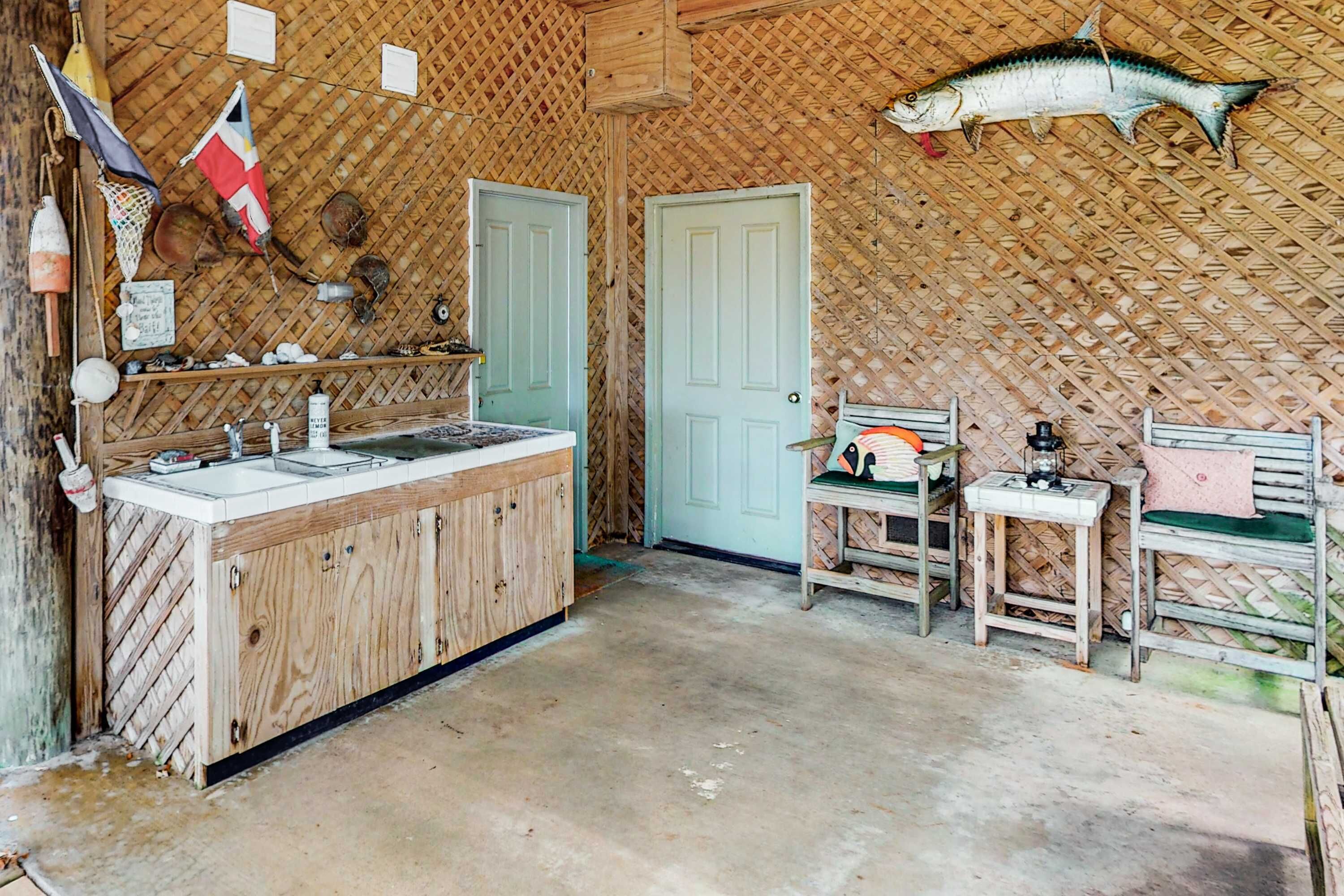 A rustic kitchen with a wooden counter, a sink, and a fish hanging on the wall.