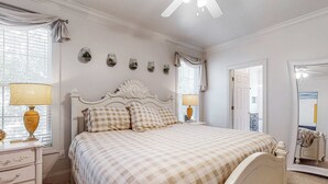 Quarto com uma cama grande, luminárias de cabeceira, cômoda e espelho.