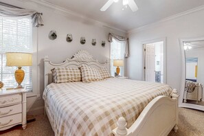Ein Schlafzimmer mit einem großen Bett, Nachttischlampen, einem Schminktisch und einem Spiegel.