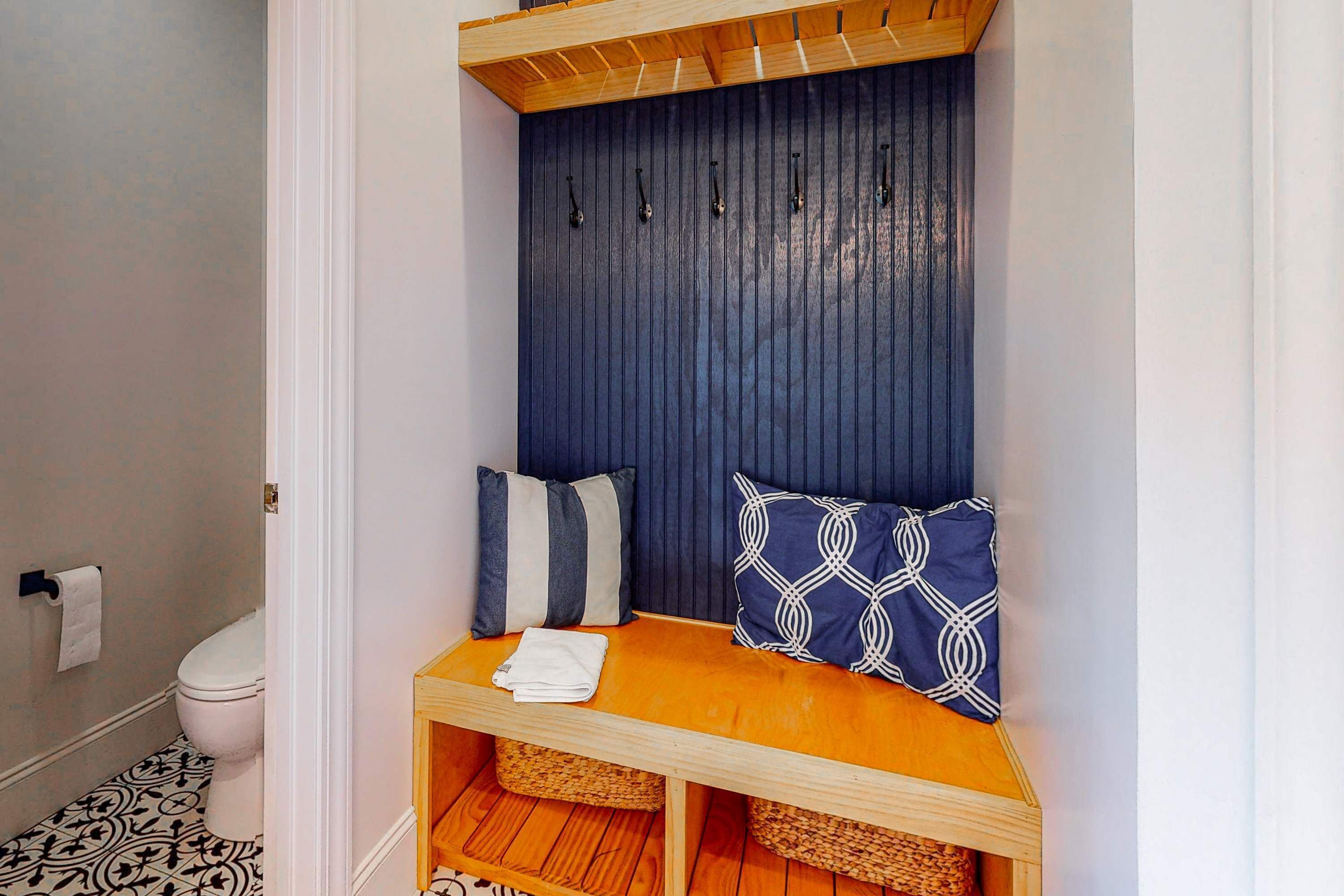 A bathroom with a toilet, a sink, and a bench with baskets underneath.