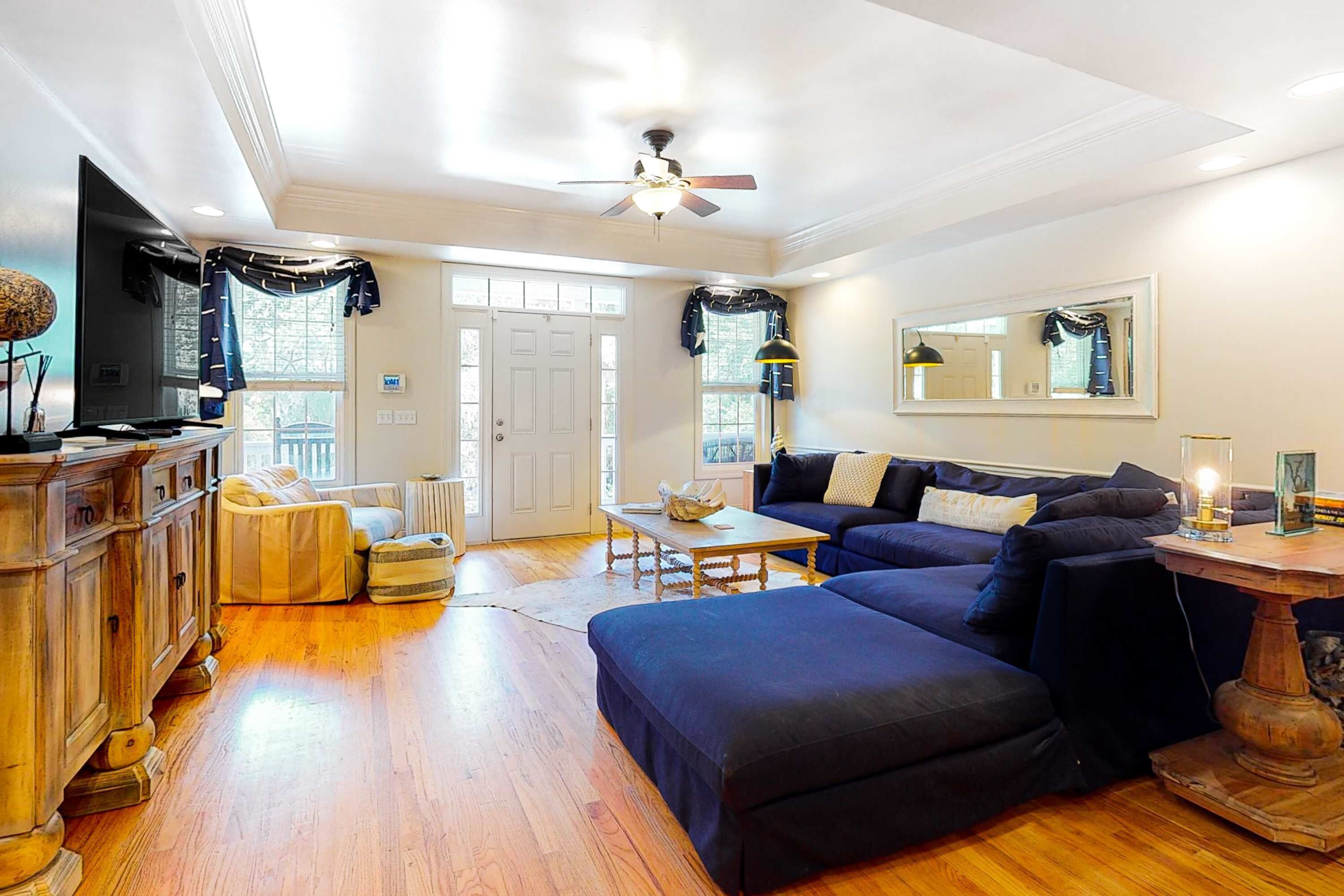 A living room with a sofa, ottoman, wooden cabinet, and a ceiling fan.