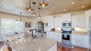 A kitchen with white cabinets, a granite countertop, stainless steel appliances, and pendant lighting. - Coastal home- Marsh Views with open floor plan and stunning sunsets (Edisto Island)